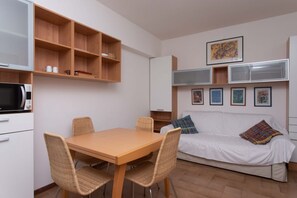 A compact living space with a dining table, wicker chairs, a white sofa, a microwave, and a TV. - M278 - Marcelli, delightful two-room apartment with terrace (Marcelli)