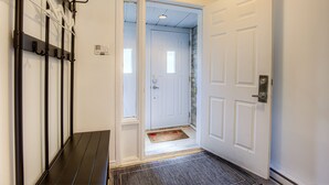A hallway with a coat rack, a door, and a doormat. - Spacious 5BR Home Near Downtown & Bell Centre | Free Parking for 2 Cars (Montréal)