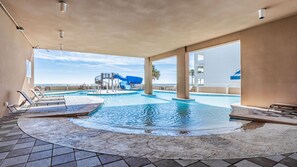 A pool area with a water slide, lounge chairs, and a view of the ocean. - New to the Rental Market, Newly Owner, Lazy river and Slide! (Orange Beach)