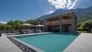 A modern pool area with a clear blue pool, lounge chairs, and umbrellas.
