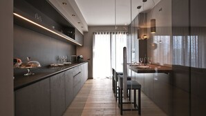 A modern kitchen with a dark countertop, built-in appliances, and pendant lighting.