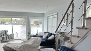 Una sala moderna con un sofá azul, un sofá blanco y una escalera.