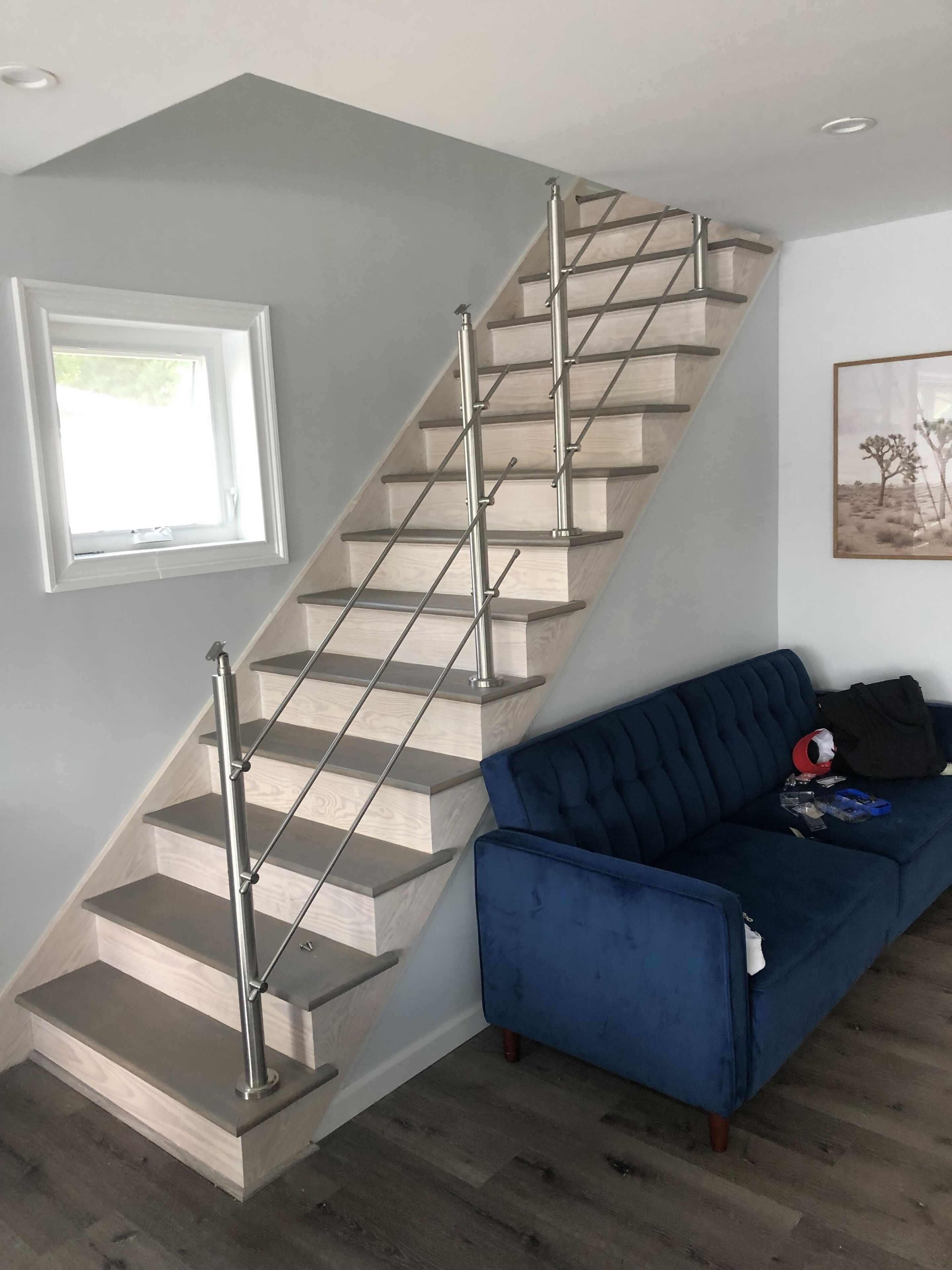 A staircase with a modern design, a blue sofa, and a framed picture on the wall.