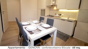 Un appartement moderne comprenant un coin repas, une kitchenette et une porte donnant sur une autre pièce.