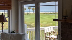 Una habitación con un amplio ventanal corredero que da a una vista de un campo de golf y el océano.