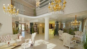 A spacious lobby with elegant chandeliers, plush seating, and a grand staircase.