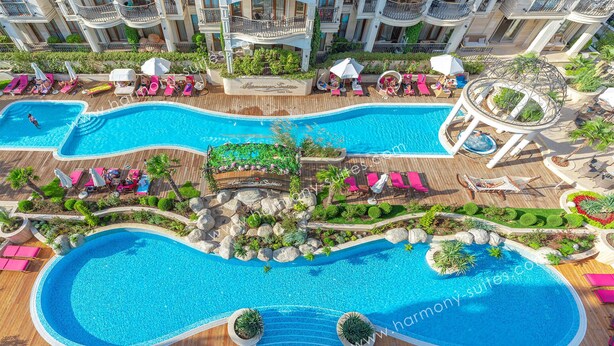 A resort with multiple swimming pools, sun loungers, and a central water feature.