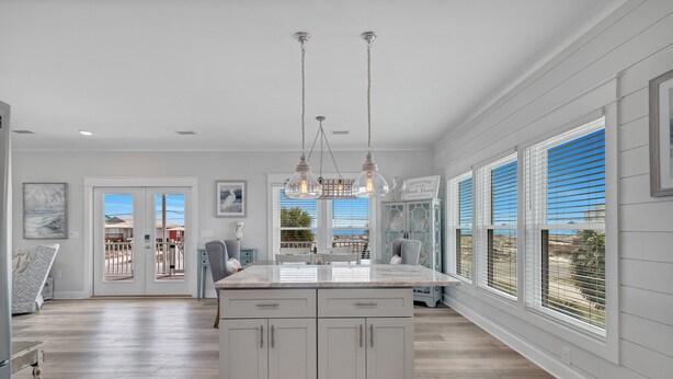 Una cocina amplia con una isla grande, muebles blancos y vistas al exterior a través de las ventanas.