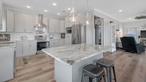 Una cocina moderna con armarios blancos, electrodomésticos de acero inoxidable y una isla de mármol.
