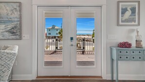 Una habitación con una puerta blanca que da a un balcón, un aparador azul claro y un cuadro en la pared.