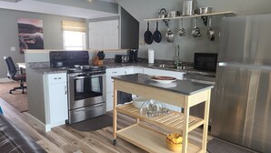 Une cuisine moderne dotée d’appareils électroménagers en acier inoxydable, d’un îlot central en bois et d’un porte-casseroles suspendu.
