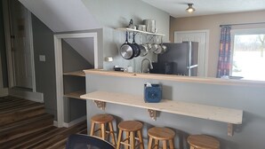 Une cuisine avec des étagères en bois, un vase bleu et un réfrigérateur.