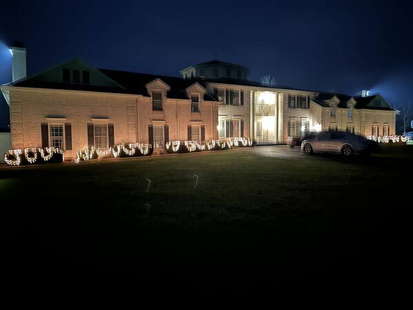 A large brick building with a well-lit entrance and a car parked in front.