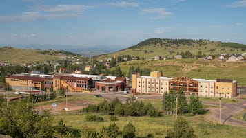 A large building with multiple floors, a parking lot, and a hilly landscape in the background.
