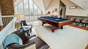 Ein geräumiger Raum mit Poolbillard, Ledersitzmöglichkeiten und einer hohen Decke mit Oberlichtern.