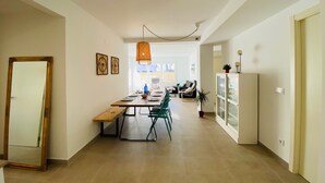 Un amplio espacio de estar con mesa de comedor, sillas, un sofá y una lámpara colgante.