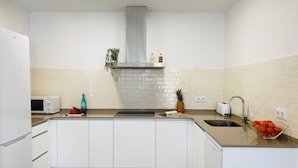 Una cocina moderna con gabinetes blancos, un lavamanos de acero inoxidable, un microondas y un tostador.