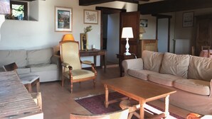 Een woonkamer met een houten tafel, twee banken, een houten stoel en een lamp.