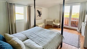 Una cama con dosel con vista a un balcón y una zona de escritorio.