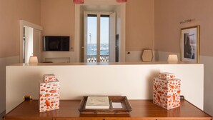 A hotel room with a large mirror, a television, a balcony with a view, and decorative boxes. - Palazzo Colombo (Gallipoli)