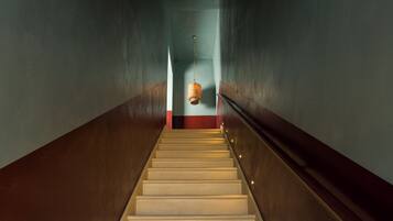 A staircase with a handrail and a hanging light fixture at the top.