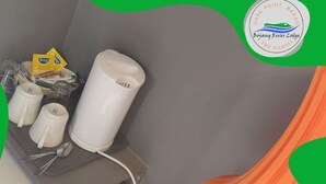 Une petite cuisine équipée d’une bouilloire blanche, de deux tasses blanches et d’une cuillère posées sur un plan de travail gris.