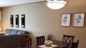 A dining area with a dark wooden table, six chairs, and a hanging light fixture. - Quiet condo at beautiful Mabel Lake (Enderby)