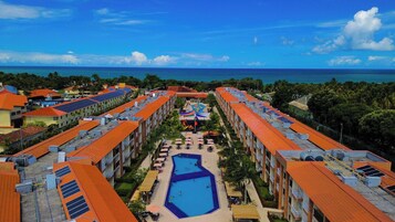 Et resort med flere bygninger, en central pool og udsigt over havet.