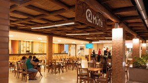 A restaurant with wooden ceiling beams, brick pillars, and tiled flooring. Tables and chairs are arranged for dining. - Ondas Praia Resort by WAM Experience  (Porto Seguro)