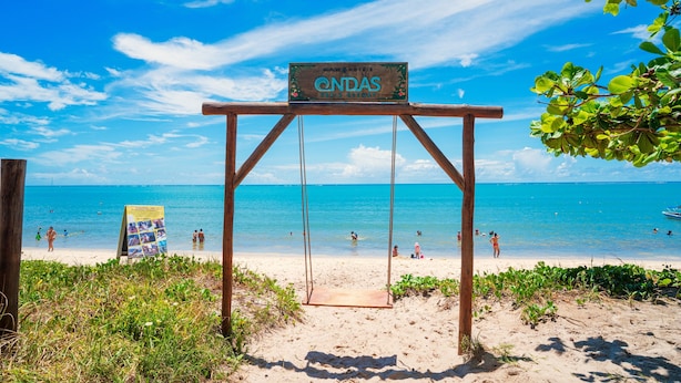 A wooden swing set with a sign reading "Candas" on a beach. - Ondas Praia Resort by WAM Experience  (Porto Seguro)