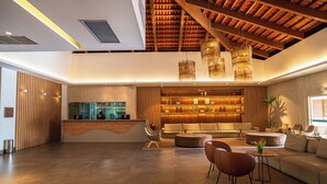 A spacious lobby with a reception desk, seating area, and a high ceiling with exposed beams. - Ondas Praia Resort by WAM Experience  (Porto Seguro)