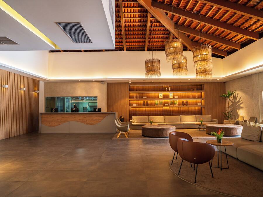 Un'ampia hall con reception, area relax e soffitto alto con travi a vista.