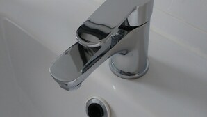 A chrome faucet with a single-handle design in a white bathtub.