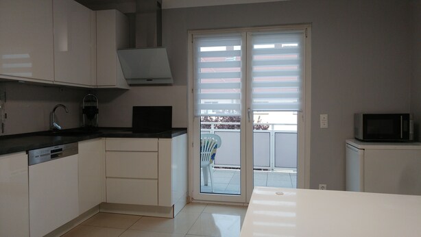 A kitchen with white cabinets, a black countertop, a microwave, and a sliding glass door leading to an outdoor area.