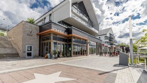 Un edificio moderno con una Starbucks en la planta baja, con amplios ventanales y un diseño de pavimento en forma de estrella.
