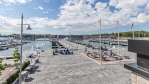 Un puerto deportivo con barcos amarrados, una zona de estar cubierta y cielo despejado.