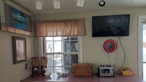 A kitchen with wooden cabinets, a window with a view, a clock, and various kitchen appliances. - Bryan Inn (Bryan)