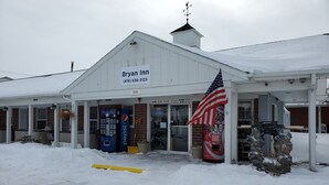 A white building with a sign reading "Bryan Inn" and a phone number. There are vending machines and a Coca-Cola dispenser outside. - Bryan Inn (Bryan)