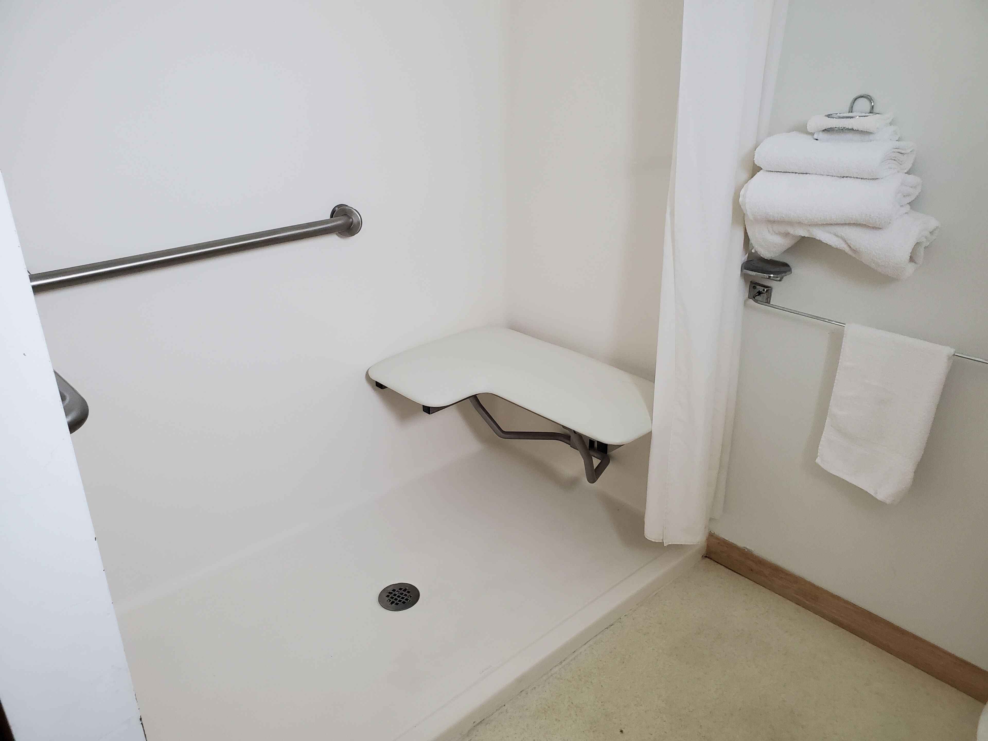 Un baño con ducha, un banco y un perchero para toallas.