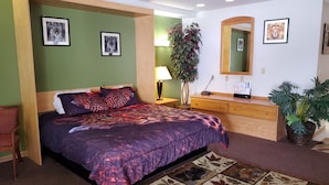 A bedroom with a bed, a dresser, a mirror, and a plant. - Bryan Inn (Bryan)