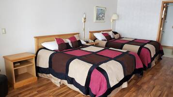 A double bed with a wooden headboard, a bedside table, a nightstand, and a wall-mounted lamp.