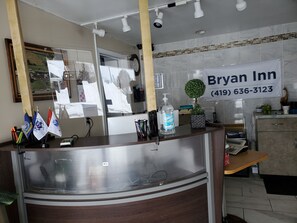 A hotel reception desk with a sign for Bryan Inn, a phone, a cash register, and flags on the left.