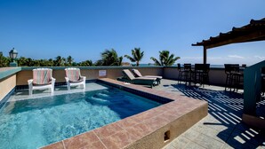 A rooftop pool with lounge chairs, a pergola, and a view of the ocean. - El Gran Castillo de Arena (San Pedro)