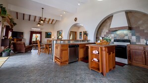 A spacious kitchen with wooden cabinetry, a central island, and a dining area with a chandelier. - El Gran Castillo de Arena (San Pedro)