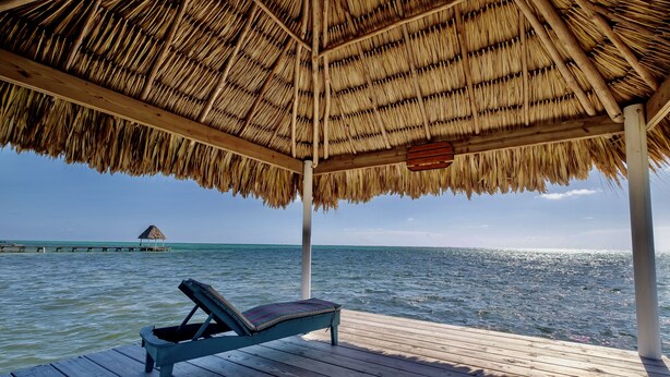 A wooden deck with a thatched roof and a lounge chair. - El Gran Castillo de Arena (San Pedro)