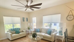 A spacious living room with two sofas, a coffee table, and a ceiling fan. - Sunset Beach Getaway – Steps to the Beach, Walk to Restaurants, Sleeps 8! (Treasure Island)