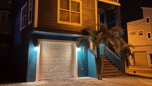 A two-story house with a garage, a balcony, and a staircase leading to the second floor. - Sunset Beach Getaway – Steps to the Beach, Walk to Restaurants, Sleeps 8! (Treasure Island)