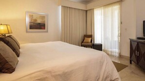 Une chambre d’hôtel équipée d’un lit, d’un ventilateur de plafond, d’une chaise, d’un bureau et d’une télévision.