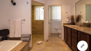 Une salle de bain équipée d’une baignoire, d’une douche, de toilettes et d’un meuble-lavabo avec un miroir.