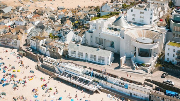 Un pueblo costero con playa, un muelle y un edificio blanco destacado con cúpula.